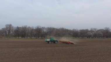 Yeşil traktör ve kırmızı ekiciler baharda tarlada çalışır. hava görünümü
