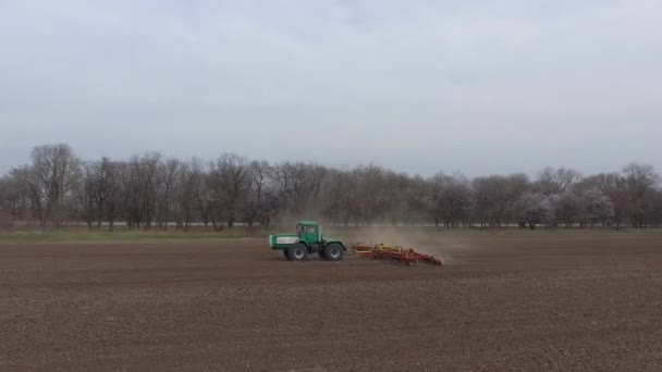 Groene trekker en rode cultivator werk in het veld in het voorjaar. vanuit de lucht bekeken — Stockvideo