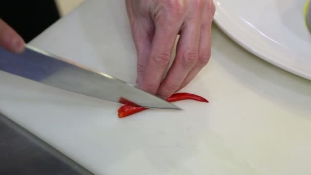 Chef taglia peperoncino rosso caldo con un coltello Video Stock