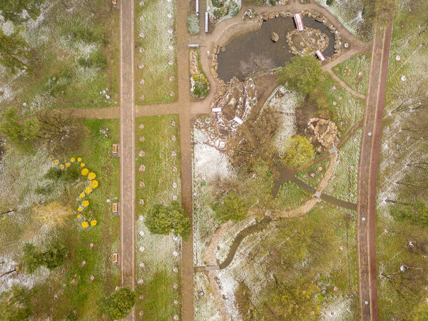 Snow on the green grass in the park in early spring. Aerial drone view.