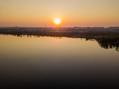 Şehirdeki gölün üzerinde gün batımı. Hava aracı görünümü.