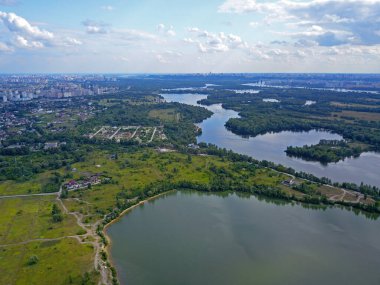 Kiev 'deki Dinyeper Nehri manzarası. Nehrin kıyısında yeşil ağaçlar. Güneşli bir bahar günü. Hava aracı görünümü