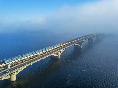 Hava görüntüsü. Metro Köprüsü, sabah erkenden. Metro treni Dinyeper nehri boyunca köprüden geçiyor.