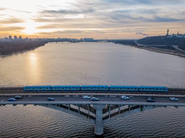 Hava görüntüsü. Metro köprüsü şafakta. Kyiv metrosu köprüden geçiyor