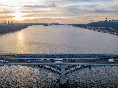 Hava görüntüsü. Metro köprüsü şafakta. Kyiv metrosu köprüden geçiyor