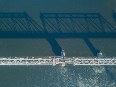 Hava aracı görüntüsü. Kiev 'deki Dinyeper Nehri üzerindeki demiryolu köprüsü. Köprünün gölgesi nehrin pürüzsüz yüzeyine düşüyor