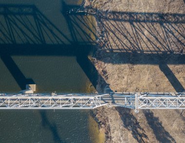 Hava aracı görüntüsü. Kiev 'deki Dinyeper Nehri üzerindeki demiryolu köprüsü. Köprünün gölgesi nehrin pürüzsüz yüzeyine düşüyor