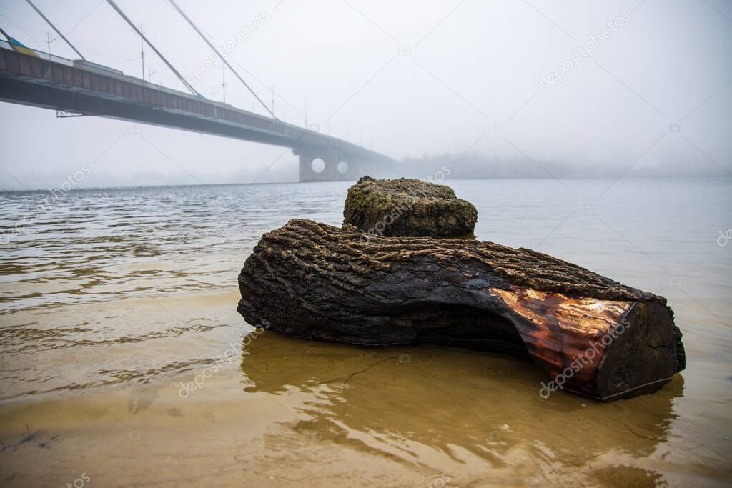 Stone on banks of Dnieper near North Bridge in Kyiv on foggy morning
