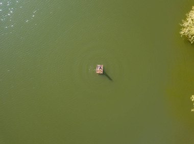 Gölün ortasındaki salda bir balıkçı. Hava aracı görünümü.