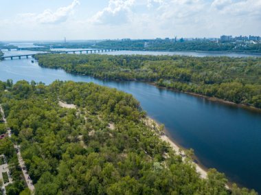 Kiev 'deki Dinyeper Nehri manzarası. Nehrin kıyısında yeşil ağaçlar. Güneşli bir bahar günü. Hava aracı görünümü.