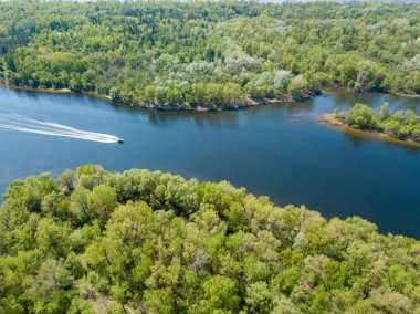 Kiev 'deki Dinyeper Nehri' nde bir motorlu tekne yüzüyor. Nehrin kıyısında yeşil ağaçlar. Güneşli bahar günü.