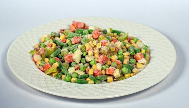 Beyaz bir tabakta donmuş sebze karışımı.