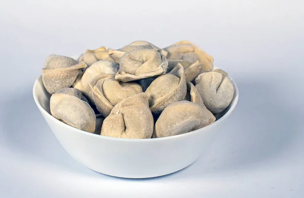 Beyaz arka planda beyaz bir tabakta donmuş hamur köftesi.