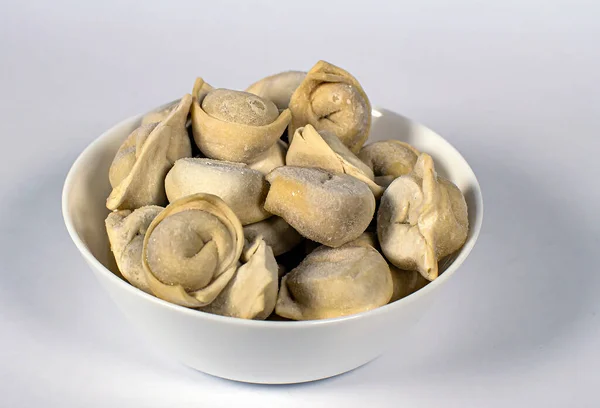 Beyaz arka planda beyaz bir tabakta donmuş hamur köftesi.