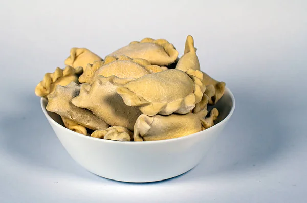 Beyaz arka planda beyaz bir tabakta donmuş hamur köftesi.