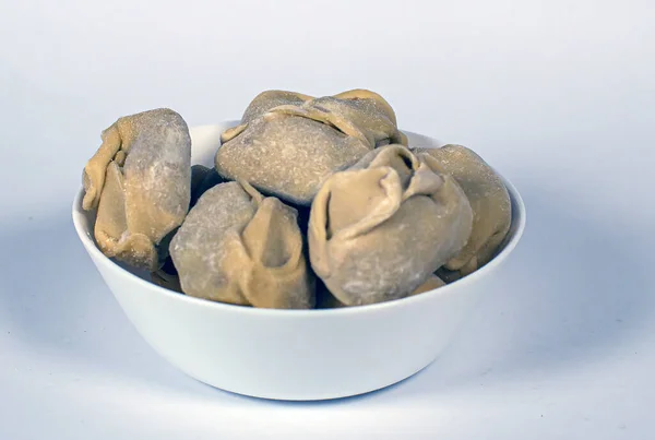 Beyaz arka planda beyaz bir tabakta donmuş hamur köftesi.