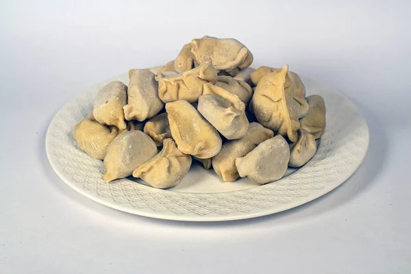 Beyaz arka planda beyaz bir tabakta donmuş hamur köftesi.