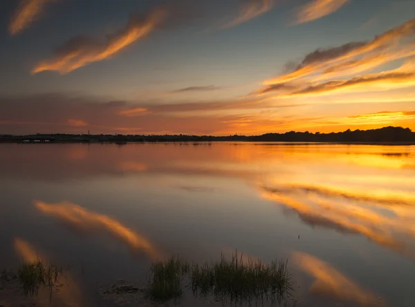 Farben des Sonnenuntergangs beleuchten Wolken, die sich perfekt in poole ha widerspiegeln — Stockfoto