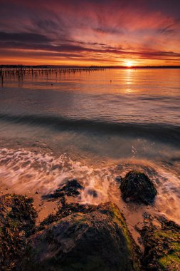 Turuncu ve kırmızı gökyüzü Sandbanks yakınındaki bir Poole Harbour iskele üzerinde derin renkler