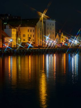 Parlak sokak ışıkları Poole Quay 'in durgun sularında yıldız şekilleri ve yansımaları yansıtıyor.