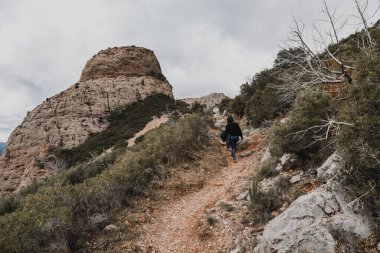 Mujer de espalda en la ruta para subir a las formaciones rocosas en Mallos de Riglos, Huesca
