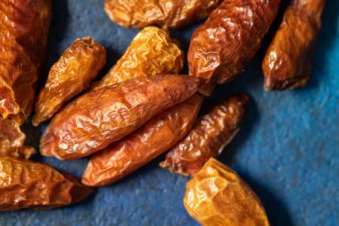 Koyu mavi arka planda yemeğe baharat eklemek için kurutulmuş kırmızı biber.