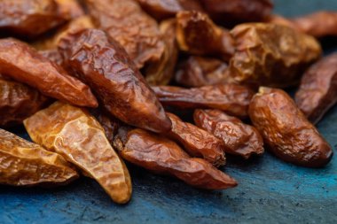 Koyu mavi arka planda yemeğe baharat eklemek için kurutulmuş kırmızı biber.