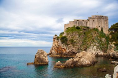 Hırvatistan 'ın Dubrovnik kentinin tarihi duvarı, güneşli bir günde kayalık kıyıda yer alıyor. 