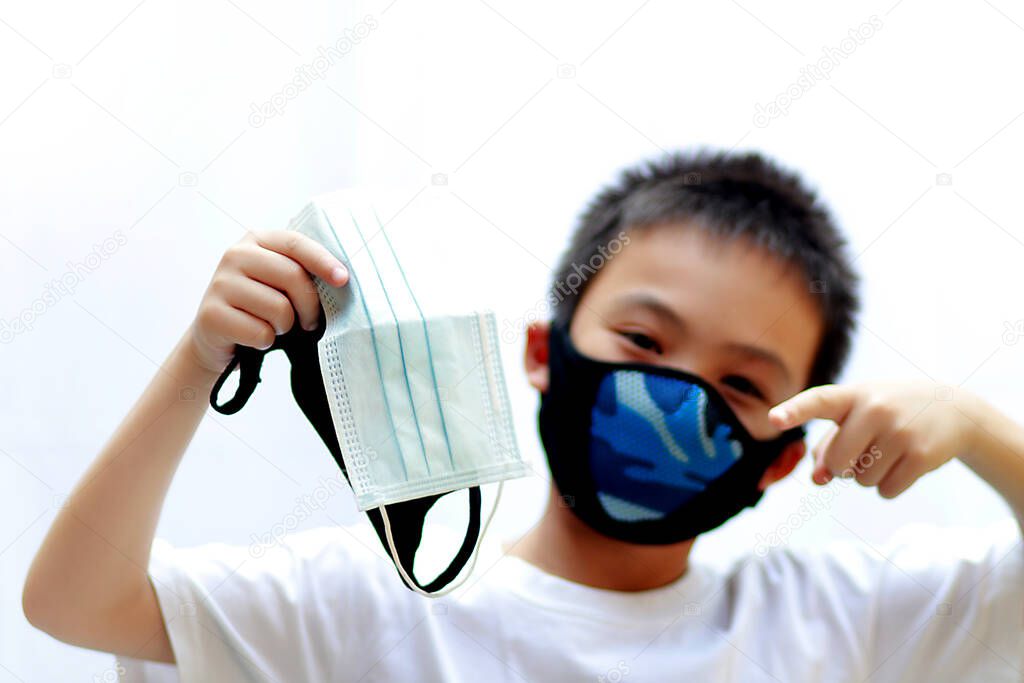 Coronavirus and Air pollution pm2.5 concept  Asian kids ware blue mask protection and holding black and white mask isolated on white background soft focus