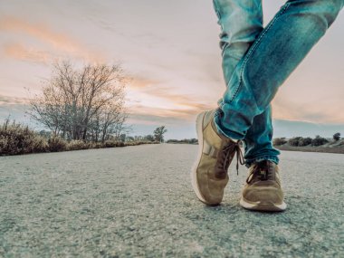 Yolu bekleyen adam. Kotlu ve kahverengi ayakkabılı bir adamın bacakları kapalı. Seçici odak