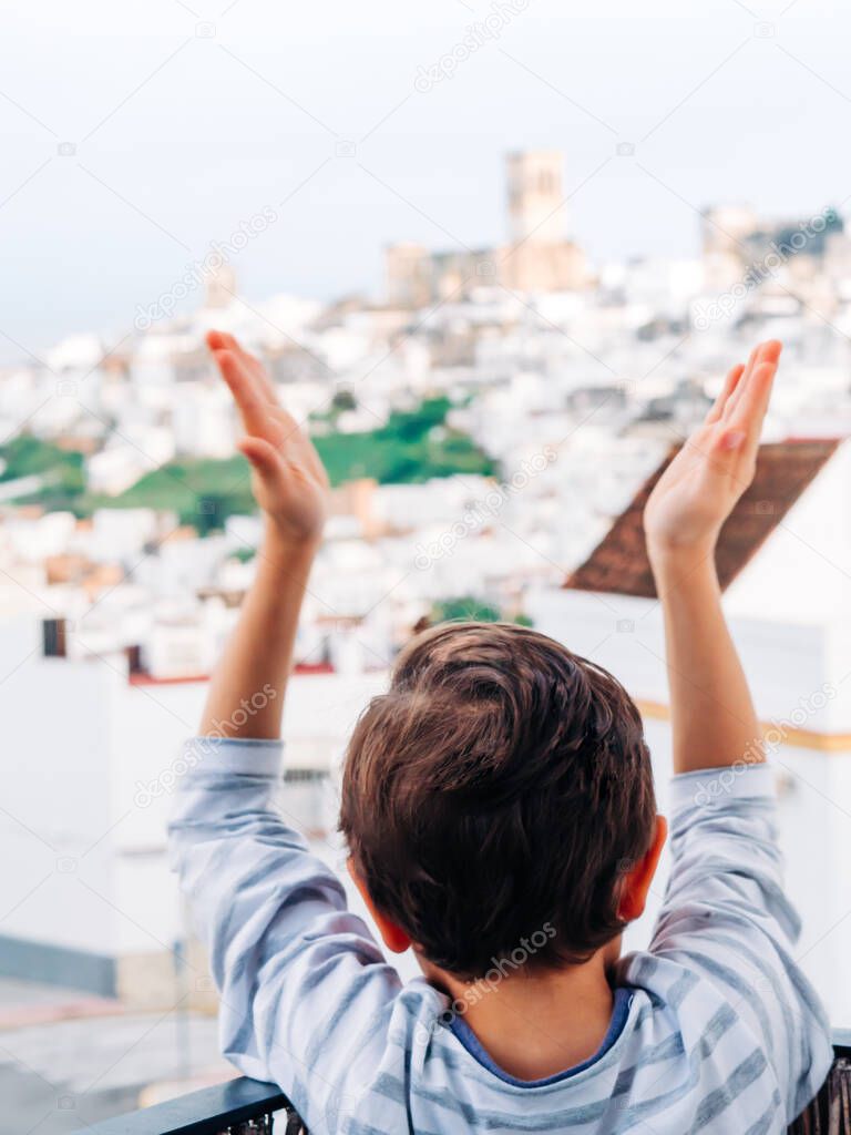 A little boy  clapping from the balcony to the doctors, nurses, hospital workers and heroes who care for us. Selective focus.