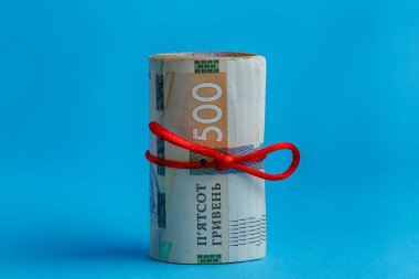 500 Hryvnia rulo kırmızı halatla sarılmış mavi bir zemin üzerinde
