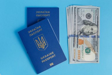 100 dolarlık bir paket banknot yurtdışında iki Ukrayna pasaportunun yanında duruyor.
