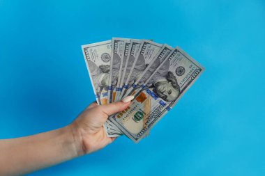 Kadın eli 100 dolarlık banknotlar gösteriyor, kadın eli para tutuyor, rehinci dükkanı kredisi reklamı, mavi arka plan