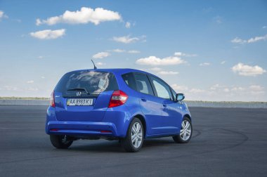 KIEV, UKRAINE-JULY 4.2017: Mavi araba Honda Jazz güneşli gökyüzünün arka planına karşı yolda park etti. Otomotiv fotoğrafçılığı. Mesaj için yer var. Arabalı arkaplan. 