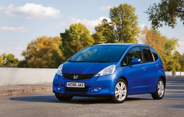 Londra, İngiltere - 20 Temmuz - Honda Jazz, sonbahar ormanının arka planına karşı yolda park etmiş mavi araba. Otomotiv fotoğrafçılığı. Mesaj için yer var. Arabayla arka plan. Özel şehir arabası Honda Jazz. 