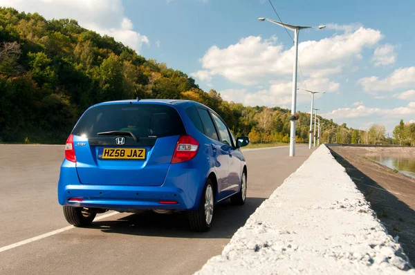 KIEV, UKRAINE - 20 Temmuz: mavi araba Honda Jazz yola park etti. Otomotiv fotoğrafçılığı. Mesaj için yer var. Arabayla arka plan. Özel şehir otomobili Honda Jazz. 