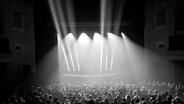 Parlak sahne ışıkları önünde siyah-beyaz konser kalabalığı. Tören sırasında kalabalık. Konser sırasında kalabalık. Sunum sırasında tiyatroda seyirciler..