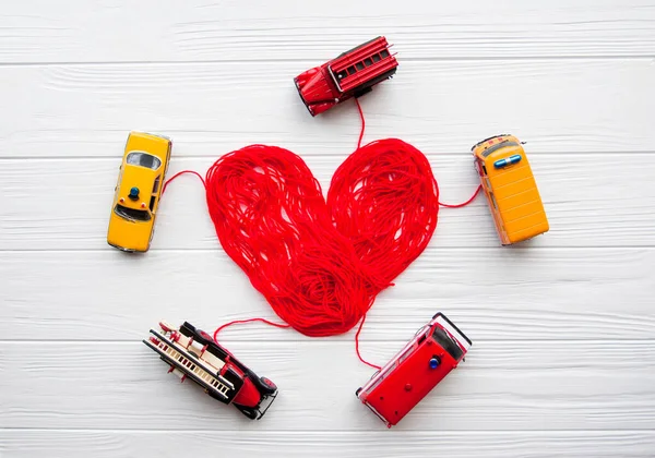 Health, medicine, people and cardiology concept. Abstract red heart with toy fire engine and police cars. Problems with heart. Heart is made of red thread. Charity, health care, donation concept. Coronavirus COVID-19