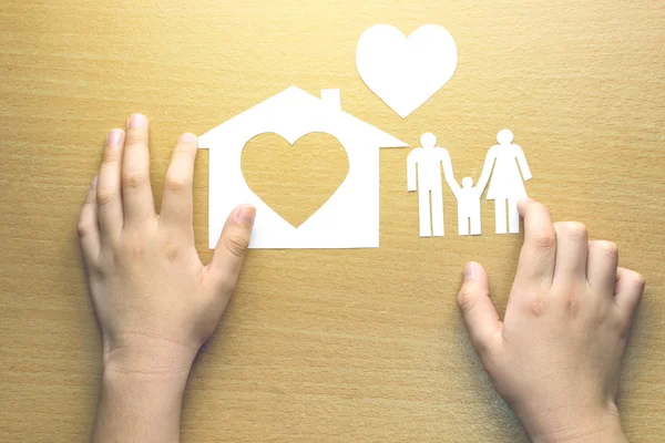 De handen van kinderen met kleine model van huis en hart en familie op — Stockfoto
