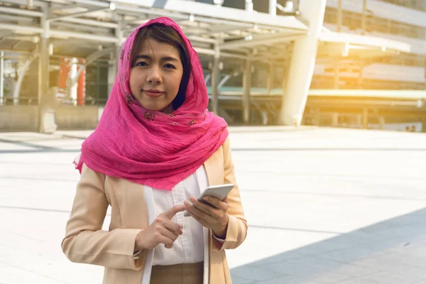 Donna musulmana messaggistica su un telefono cellulare in città — Foto Stock
