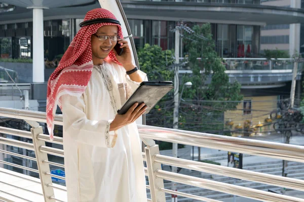 Arab businessman using tablet and mobile phone.