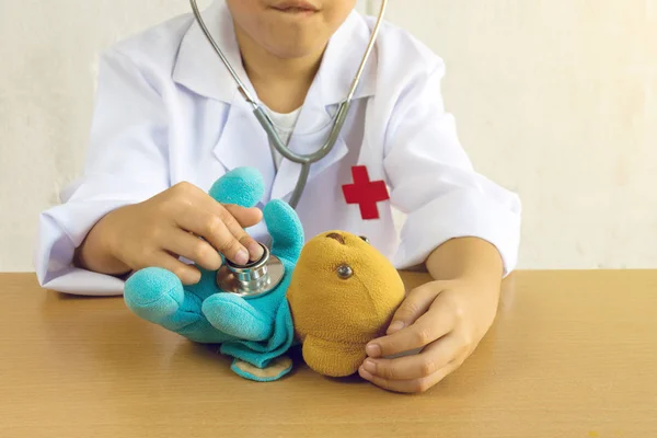 Asian boy playing as a doctor care bear doll
