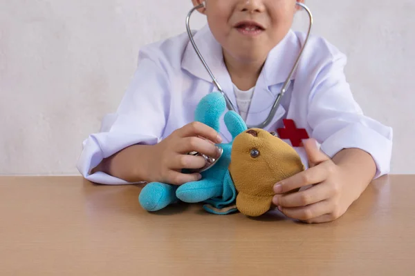 Ásia menino jogar como um médico cuidados urso boneca — Fotografia de Stock