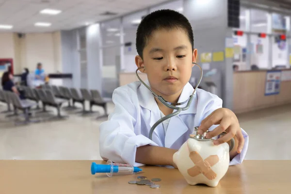 Ásia menino jogar como um médico cuidado porquinho banco — Fotografia de Stock