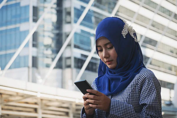 Donna musulmana messaggistica su un telefono cellulare in città — Foto Stock