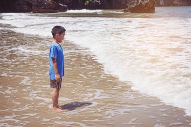 Küçük çocuk kumsalda oynuyor.