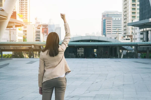 Winner woman celebrating success on city background.