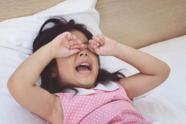 Asian little girl crying on bed