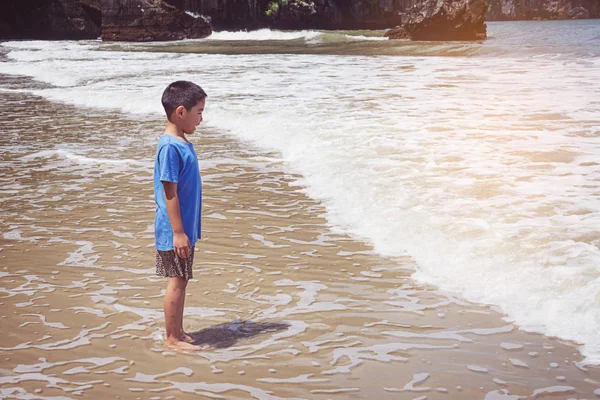 Küçük çocuk kumsalda oynuyor.